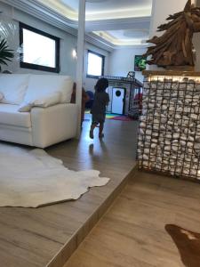 ein kleines Kind, das durch ein Wohnzimmer mit einem Sofa geht in der Unterkunft Hotel Bellariva in Lido di Jesolo