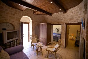 een woonkamer met een bank, stoelen en een tv bij Trulli e Puglia Resort in Alberobello