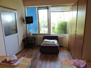 a room with a bed and a chair and windows at Vila Chasovnikarov in Golden Sands