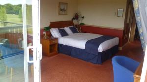 a hotel room with a bed and a balcony at London Beach Country Hotel & Golf Club in Tenterden