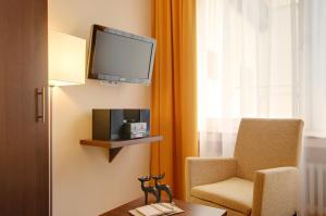 a room with a chair and a television on a wall at Hotel Mercedes City in Bonn