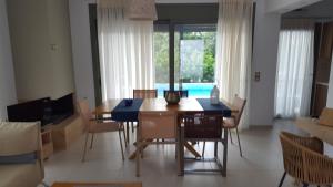 a dining room with a table and chairs and a pool at Ionian Green Villas in Preveza