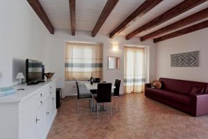 a living room with a red couch and a table at Agriturismo Casale Degli Ulivi Alghero in Santa Maria la Palma