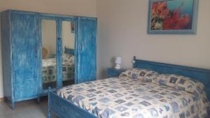 a bedroom with a blue bed and a mirror at B&B Le Peonie in Badesi
