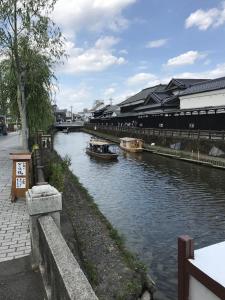 Un río con barcos dentro con un edificio en Guest House Kuranomachi ゲストハウス蔵の街, en Tochigi