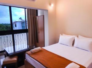 a bedroom with a bed and a large window at Monarch Palms- Serviced Apartments (Managed by HNH Homes) in Candolim