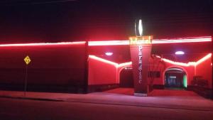 een rood gebouw met 's nachts een bord ervoor bij Motel Paradise (Adults only) in São José dos Campos