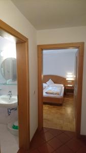 uma casa de banho com um quarto com uma cama e um lavatório em Residence Ploner em San Cassiano