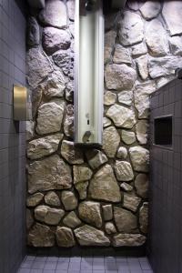 La salle de bains est pourvue d'une douche et d'un mur en pierre. dans l'établissement Eurohostel, à Helsinki