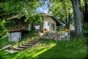 a small house with a stone retaining wall and stairs at Pamario Krašto Sodyba in Grumbliai