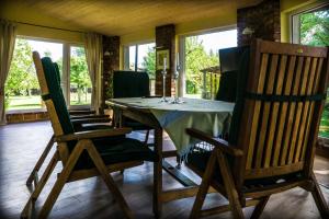 a dining room with a table and chairs and windows at Pamario Krašto Sodyba in Grumbliai