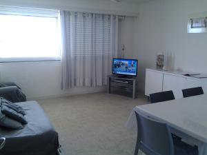 een woonkamer met een tv en een tafel bij Résidence La Garenne à La Grande Plage, vue mer, piscine et parking privé, 6 personnes in Saint-Gilles-Croix-de-Vie