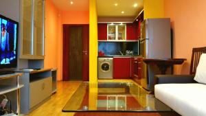 a living room with orange walls and a kitchen with a tv at Apartment Asen Apartments - ул Петко Д Петков 64 in Plovdiv