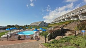 a pool with blue umbrellas and stairs next to a building at Beachcomber Resort at Montauk in Montauk