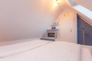 ein Schlafzimmer mit einem weißen Bett und einem Herd in der Unterkunft Haus Anke, Wohnung Muschelsucher, Westerlandstr. 37 in Wenningstedt-Braderup