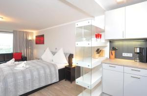 ヴェスターラントにあるSylter-Mitteの白いベッドルーム(ベッド1台付)、キッチンが備わります。