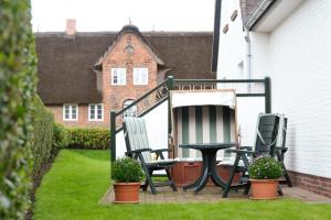 2 Gartenstühle und ein Tisch auf der Veranda in der Unterkunft Wohnung Sylthome in Westerland