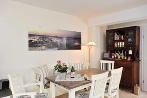 a dining room with a table and white chairs at Meerwievke in Tinnum