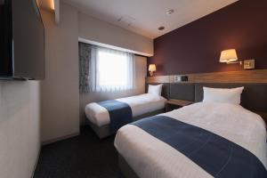 津市にあるホテル　ザ・グランコート津西のベッド2台と窓が備わるホテルルームです。