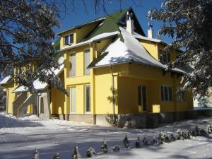 a yellow house with snow on the ground at Apartments Beljić in Divčibare