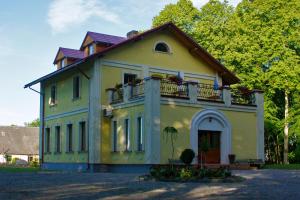 a yellow house with a balcony on top of it at Leču muiža in Lēči