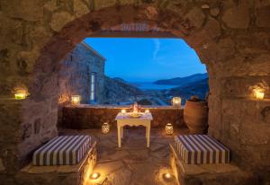 a stone room with a table and chairs and a window at Theologos Houses in Grikos