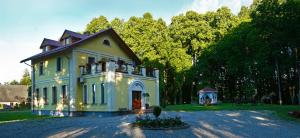 a large yellow house with trees in the background at Leču muiža in Lēči