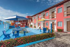 a pool with tables and umbrellas in a courtyard at Pousada Lua de Tomate in Porto Seguro