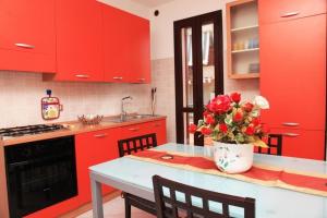 アルゲーロにあるCasa Rosada Algheroの赤いキャビネットと花瓶付きのテーブルが備わるキッチン