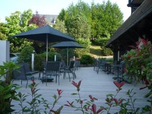 a patio with tables and chairs and umbrellas at Best Western Plus Hostellerie Du Vallon in Trouville-sur-Mer