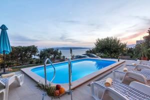 a swimming pool with chairs and a table with fruit on it at Vila Dunja in Makarska