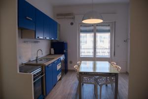 マリーナ・ディ・グロッセートにあるWonderful house in Marina di Grossetoのキッチン(青いキャビネット、ガラスのテーブル付きの小さなテーブル付)