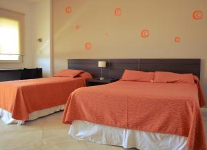 1 dormitorio con 2 camas con sábanas de color naranja y ventana en Hotel La Posada del Viajero en Río Cuarto