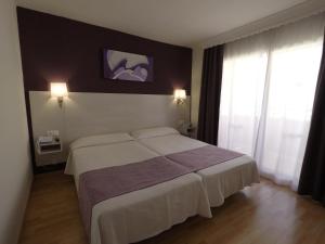 a bedroom with a large bed and two windows at Ona Princesa Playa in Marbella