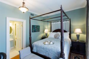 a bedroom with a canopy bed and a bathroom at Historic Lyons House in Niagara on the Lake