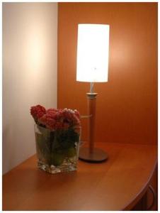 a lamp and a vase of flowers on a table at Hotel South Charleroi Airport in Charleroi