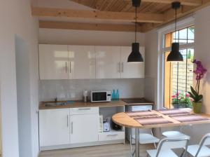 cocina con armarios blancos y mesa de madera en Furedi virag villa, en Balatonfüred