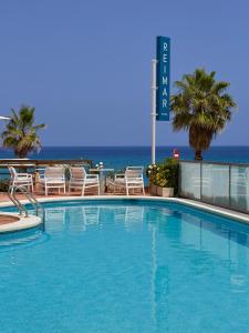 a swimming pool with chairs and the ocean in the background at Hotel Reimar in Sant Antoni de Calonge