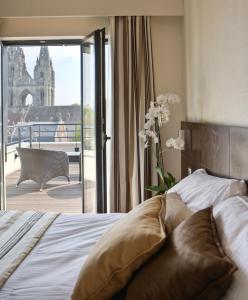 a bedroom with a bed and a balcony with a building at Best Western Plus Hotel des Francs in Soissons