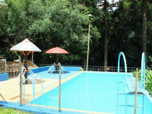 uma piscina azul com guarda-sóis e cadeiras e uma piscina em Hotel Pousada Mata Nativa em Passo Fundo