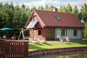 a house with people sitting in chairs in the yard at Lodges Zacisze I in Giżycko