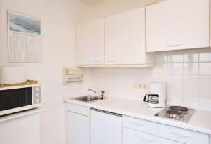 a white kitchen with a sink and a microwave at Appartment-19-Sylter-Robbe in Wenningstedt