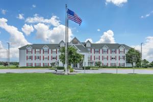 a large white building with an american flag at Lancaster Inn & Suites in Manheim