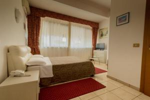 a bedroom with a bed and a desk and a window at Hotel Giulietta e Romeo in Casal Palocco