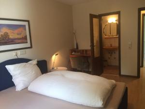 Schlafzimmer mit einem Bett mit weißer Bettwäsche und einem Spiegel in der Unterkunft ICC Pfälzer Hof - Hotel & Seminarhaus in Schönau