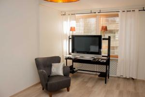 a living room with a television and a chair at Kotimaailma Alex 1 in Lahti