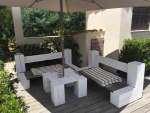 two benches and a table and an umbrella on a deck at Villa La Begude in Saint-Tropez