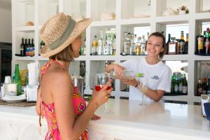 a woman standing in front of a counter with a bottle of wine at Hotel Del Levante in Torre Canne