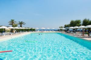 a pool at a resort with umbrellas and a beach at Hotel Del Levante in Torre Canne