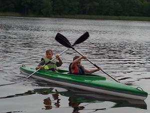 two children are in a kayak on the water at Cudodomek na Mazurach w Woszczelach koło Ełku in Ełk